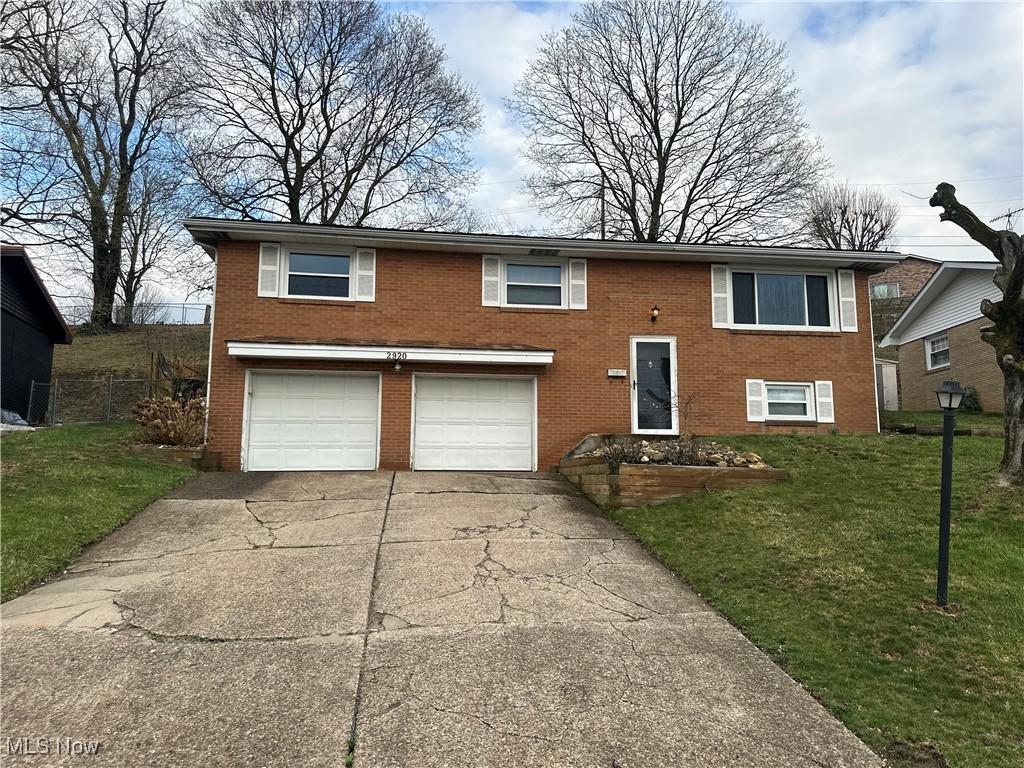 view of front of house with driveway, a front yard, a garage, and brick siding