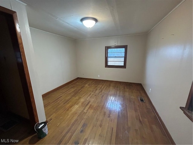 spare room featuring baseboards, visible vents, and wood-type flooring