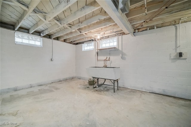 basement featuring concrete block wall and a sink