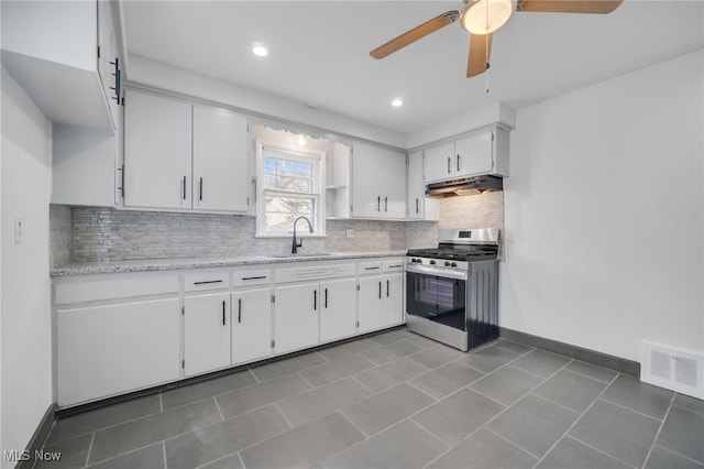 kitchen with a sink, a ceiling fan, white cabinetry, under cabinet range hood, and gas stove
