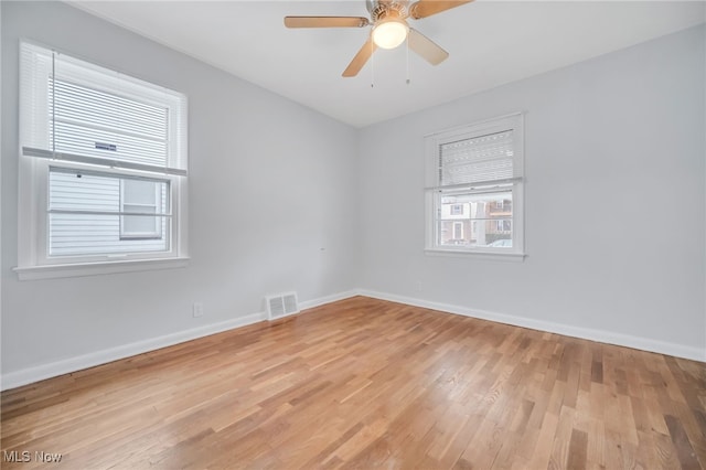 unfurnished room featuring a ceiling fan, light wood-style flooring, baseboards, and visible vents