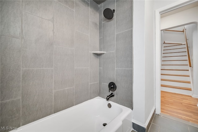 bathroom featuring baseboards, wood finished floors, and shower / bath combination