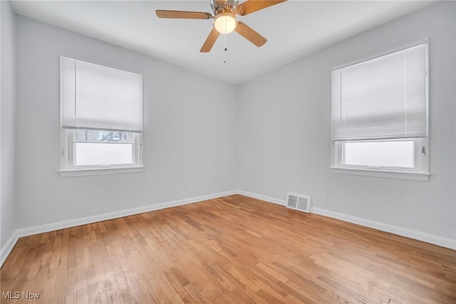 empty room with baseboards, ceiling fan, visible vents, and light wood finished floors