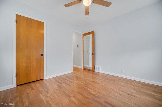 empty room featuring light wood finished floors, baseboards, visible vents, and ceiling fan
