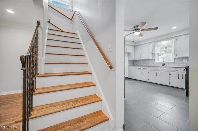 stairs with ceiling fan and recessed lighting