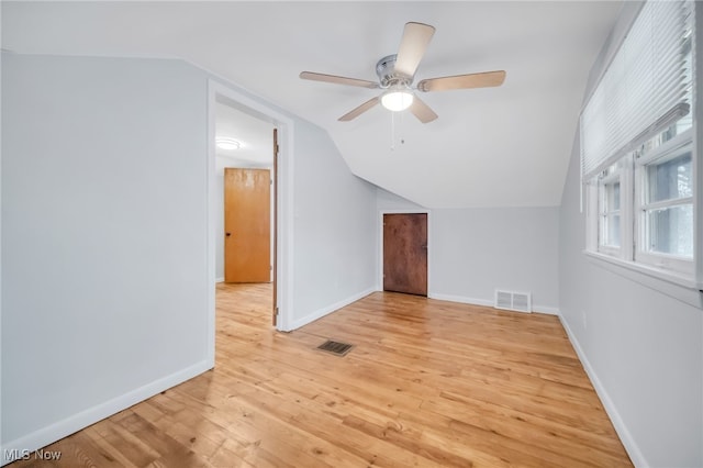 additional living space featuring light wood-style flooring, visible vents, baseboards, ceiling fan, and vaulted ceiling