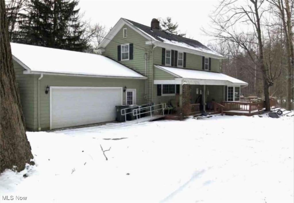 view of front of property featuring an attached garage, a chimney, and a wooden deck