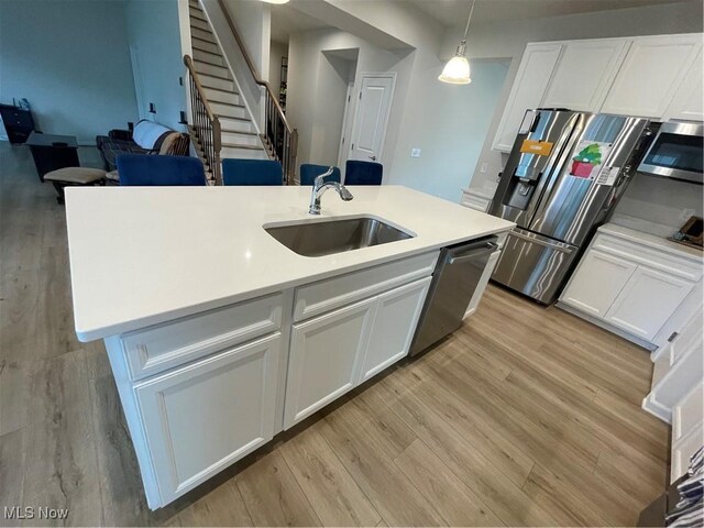 kitchen with light wood-style flooring, appliances with stainless steel finishes, a sink, and white cabinetry