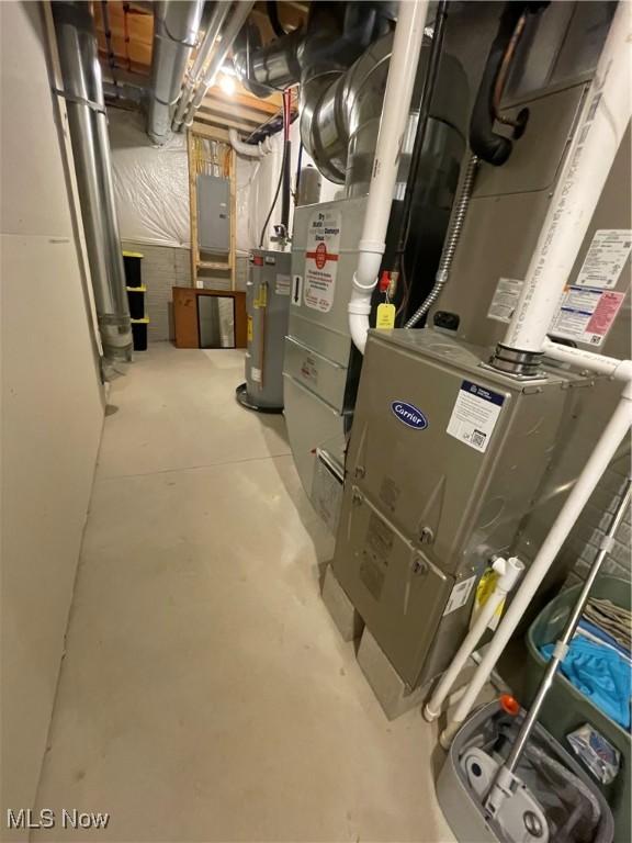 utility room with electric panel, water heater, and heating unit