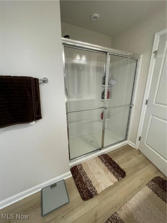 bathroom featuring a stall shower, wood finished floors, and baseboards