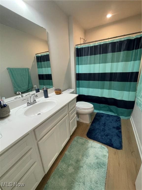 full bathroom with vanity, a shower with curtain, toilet, and wood finished floors