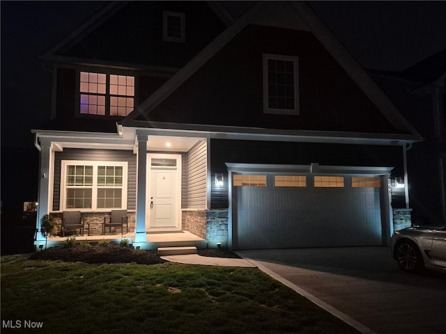 view of front of property with a porch, stone siding, and driveway