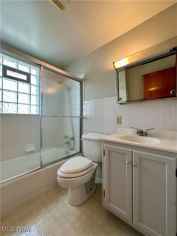 1563 Maplewood St NE, Warren, OH 44483 - full bathroom with bath / shower combo with glass door, toilet, vanity, and tile walls