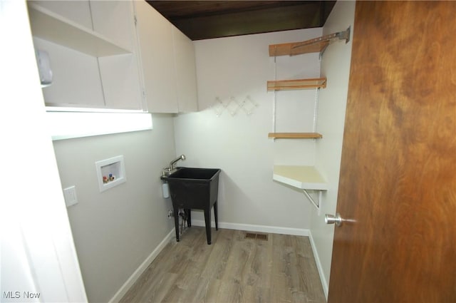 washroom with baseboards, hookup for a washing machine, light wood-style flooring, and visible vents