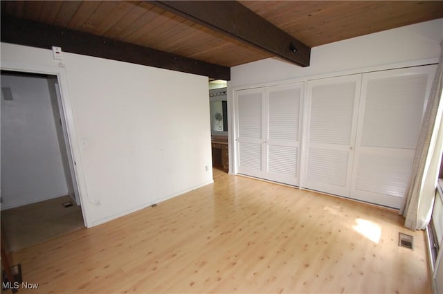 unfurnished bedroom with visible vents, wood ceiling, wood finished floors, multiple closets, and beam ceiling