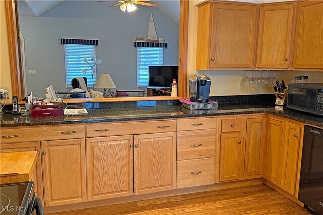 103 Southaven Ln, Kelleys Island, OH 43438 - kitchen with lofted ceiling, dark stone counters, light wood finished floors, a ceiling fan, and black appliances