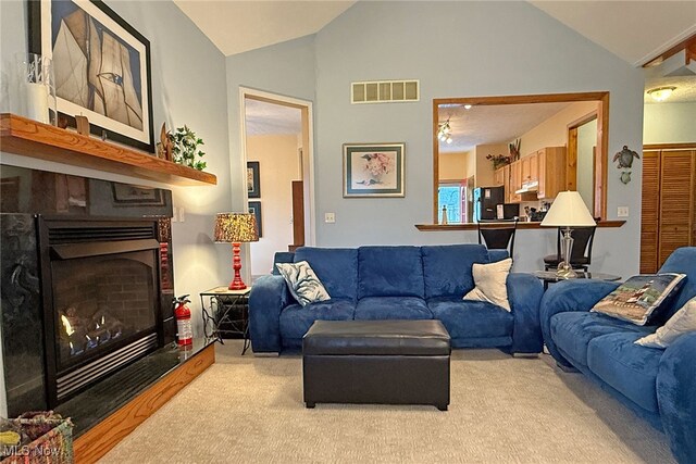 103 Southaven Ln, Kelleys Island, OH 43438 - living area with a fireplace with raised hearth, visible vents, vaulted ceiling, and light carpet