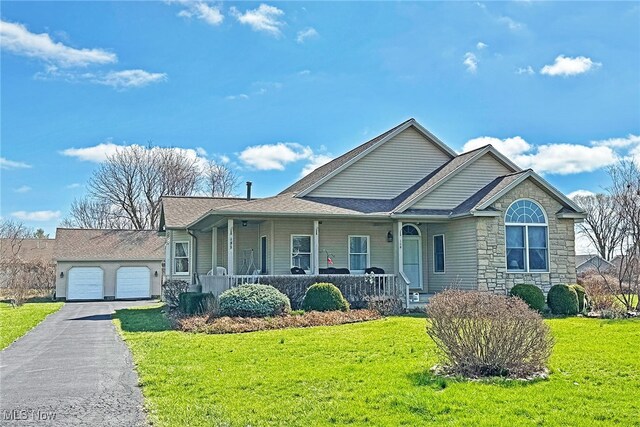 103 Southaven Ln, Kelleys Island, OH 43438 - view of front of house with covered porch, stone siding, aphalt driveway, a front lawn, and a garage