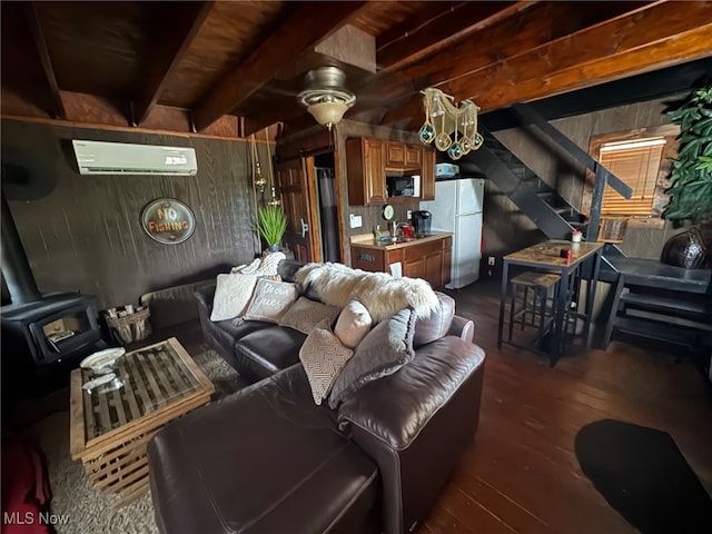 7301 Leafygreen St SW, Carrollton, OH 44615 - living room with a wall mounted AC, a wood stove, stairs, dark wood-style floors, and beam ceiling