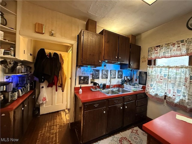 kitchen with dark wood-type flooring, a sink, dark countertops, and dark brown cabinets
