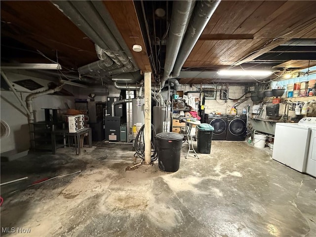 unfinished basement featuring heating unit, gas water heater, and independent washer and dryer