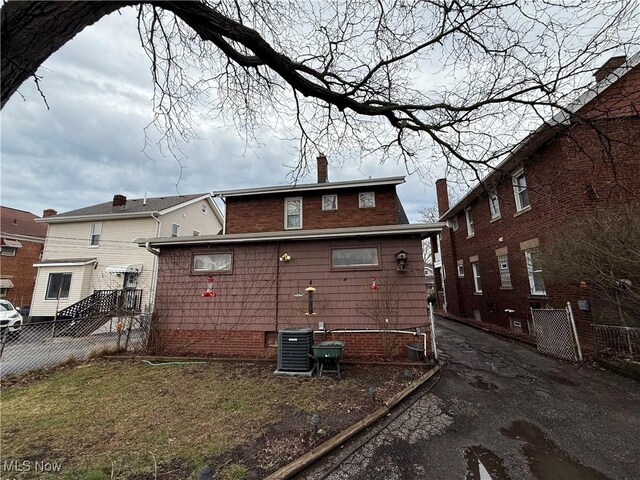 back of house featuring a chimney, fence, and central AC