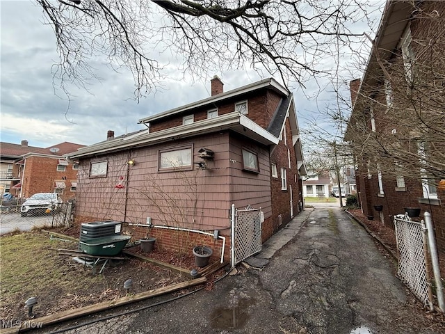 view of property exterior with crawl space, a chimney, and fence