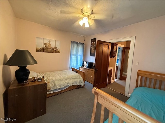 bedroom featuring a textured ceiling, dark carpet, and a ceiling fan