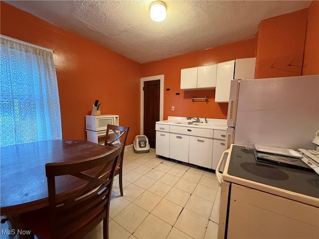 kitchen with white appliances, white cabinets, a sink, and a textured ceiling