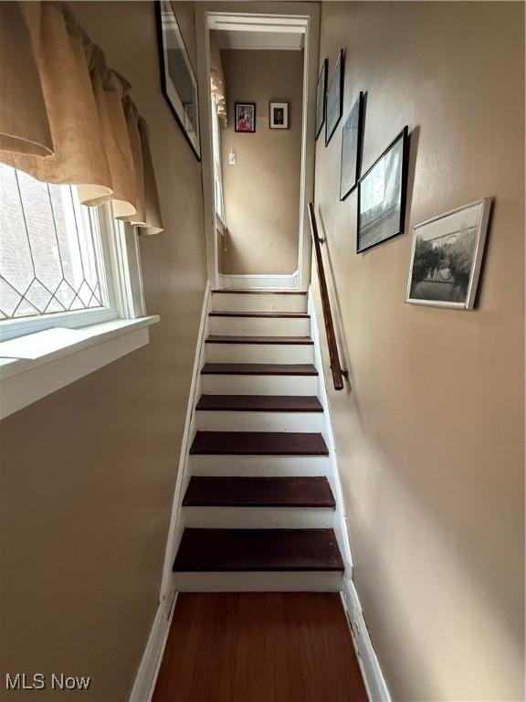 staircase with baseboards and wood finished floors