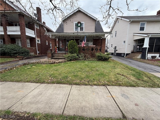 view of front of property featuring driveway, brick siding, and a front lawn