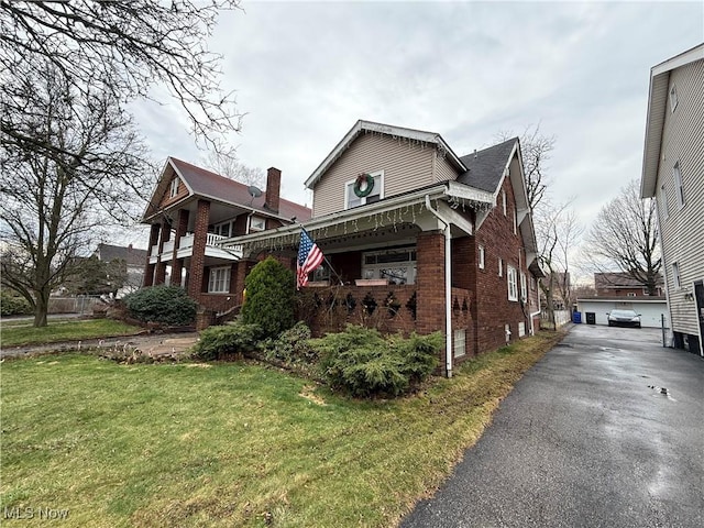 view of front of house featuring an outdoor structure, brick siding, a front yard, and a garage