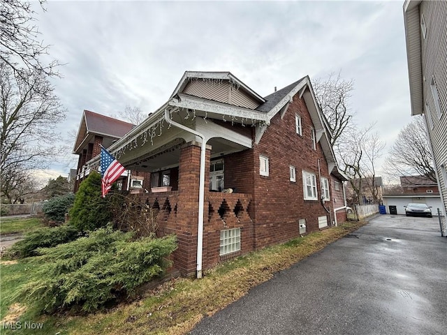 view of side of property featuring an outdoor structure, brick siding, and a garage