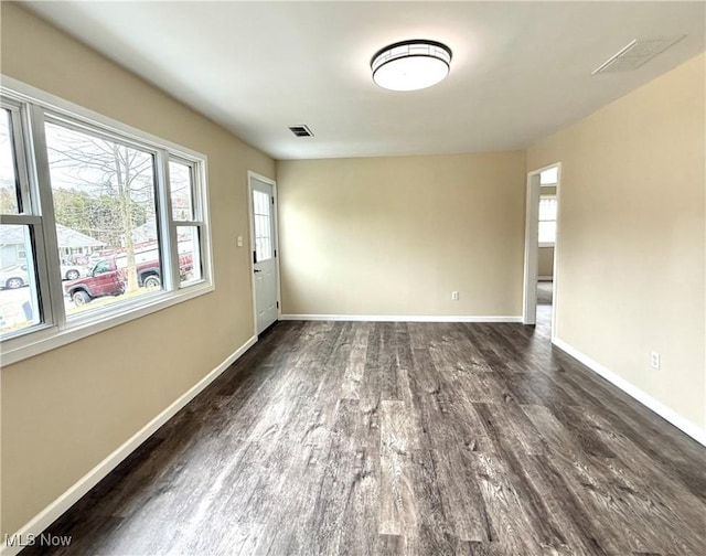empty room with visible vents, baseboards, and wood finished floors