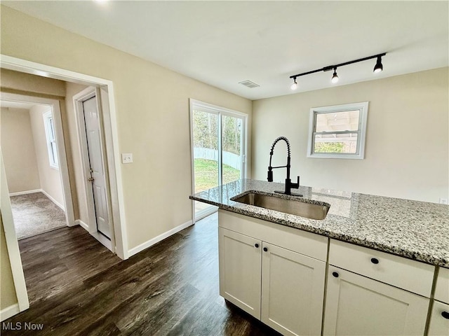 kitchen with light stone counters, a sink, white cabinetry, dark wood finished floors, and visible vents