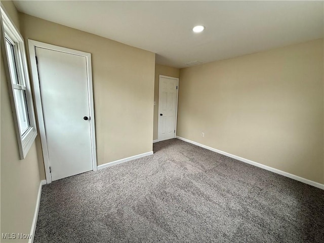 empty room with carpet floors, baseboards, visible vents, and recessed lighting
