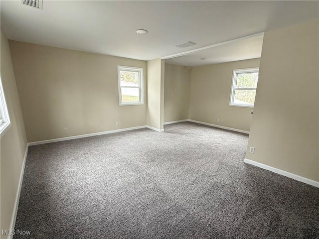 carpeted spare room with baseboards, visible vents, and a healthy amount of sunlight