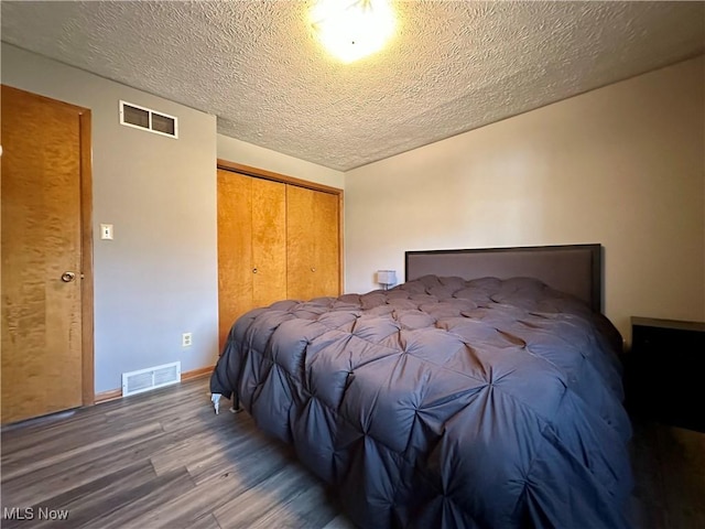 bedroom with visible vents, a textured ceiling, wood finished floors, and a closet