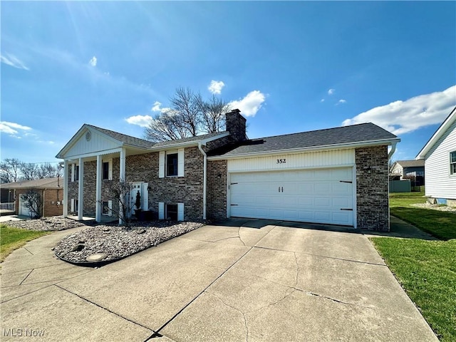 view of front of house featuring concrete driveway, brick siding, a chimney, and a garage