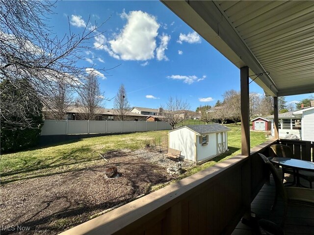 exterior space featuring a storage unit, fence, an outbuilding, and a residential view