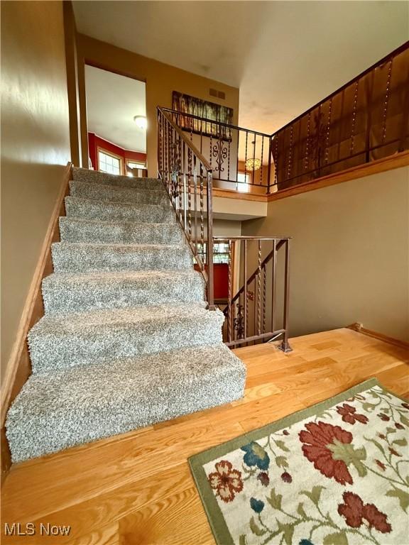 staircase featuring visible vents and wood finished floors