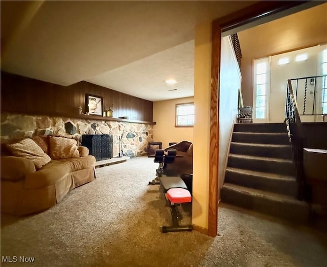 living room featuring carpet flooring, stairs, wooden walls, and a fireplace