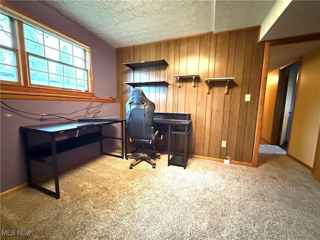 home office featuring baseboards, carpet, wood walls, and a textured ceiling