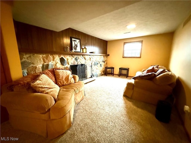 living room featuring carpet, wood walls, and a stone fireplace