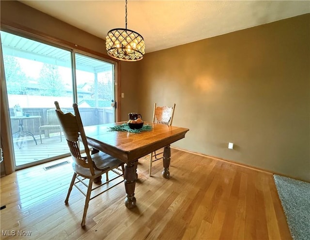 dining area with visible vents, light wood-type flooring, and a chandelier