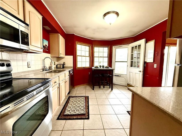 kitchen featuring a sink, decorative backsplash, appliances with stainless steel finishes, and light tile patterned floors