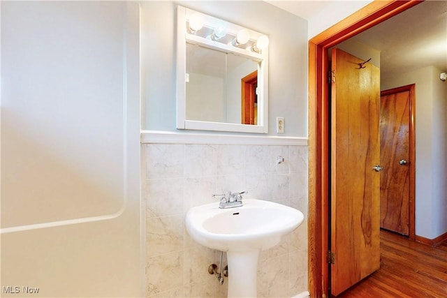 bathroom featuring a wainscoted wall, a sink, tile walls, and wood finished floors