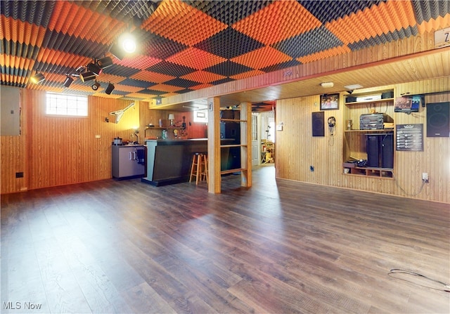 interior space with electric panel, wooden walls, and wood finished floors
