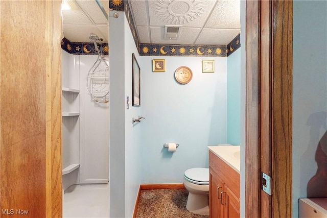 bathroom with visible vents, baseboards, toilet, vanity, and a drop ceiling