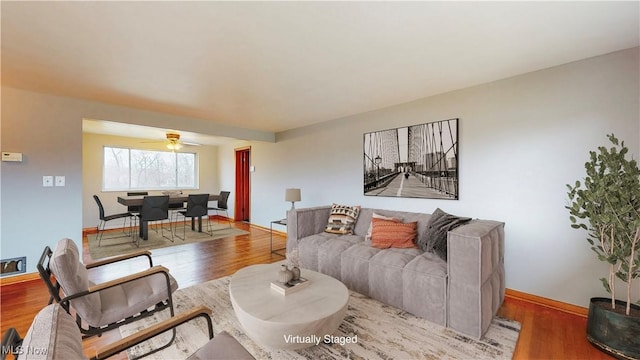 living room with baseboards, wood finished floors, and a ceiling fan
